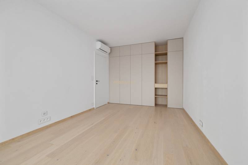 An empty room with a wooden floor, built-in wardrobe, and air conditioning in a 2-room apartment.