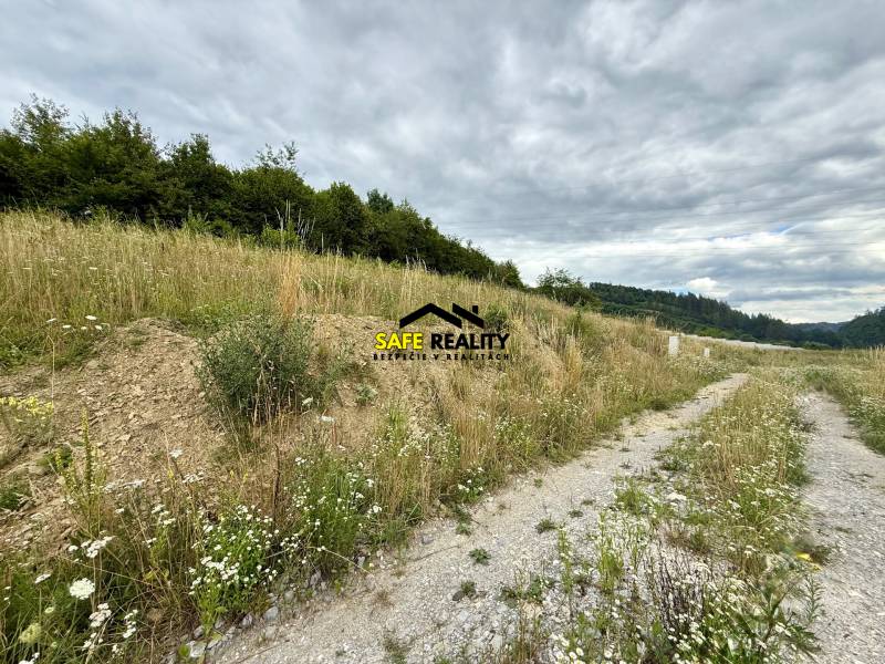 Plots - housing in Divinka with grass, trees, and a road under a cloudy sky.
