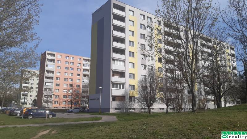 An apartment building in Trnava surrounded by trees with parking spaces, suitable for a 3-room apartment.