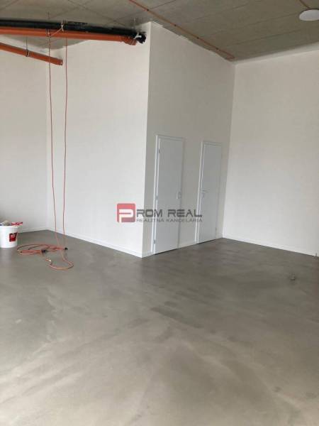 An empty space with a concrete floor and doors in commercial premises.
