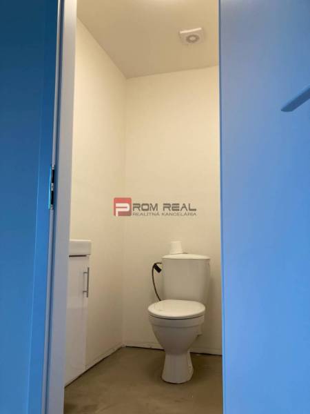 A toilet in a white space with a toilet bowl and a sink. Commercial premises.