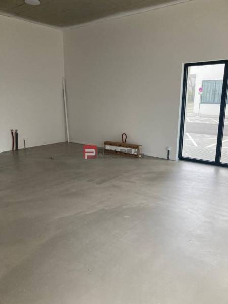 Unfurnished commercial spaces with large windows and concrete flooring.