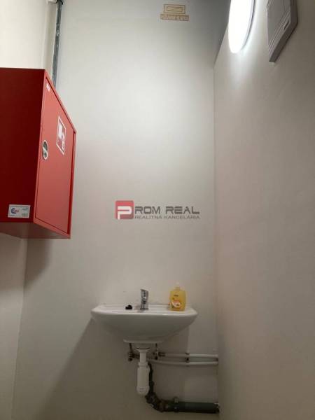 A small sink with yellow soap next to a red cabinet in commercial premises.