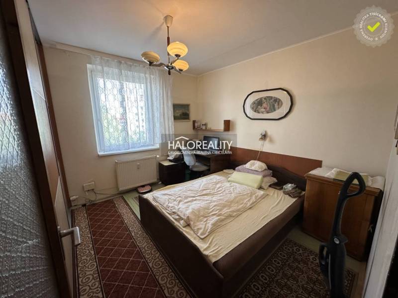 Bedroom in a 3-room apartment with a bed, painting, and carpets, suitable for living.