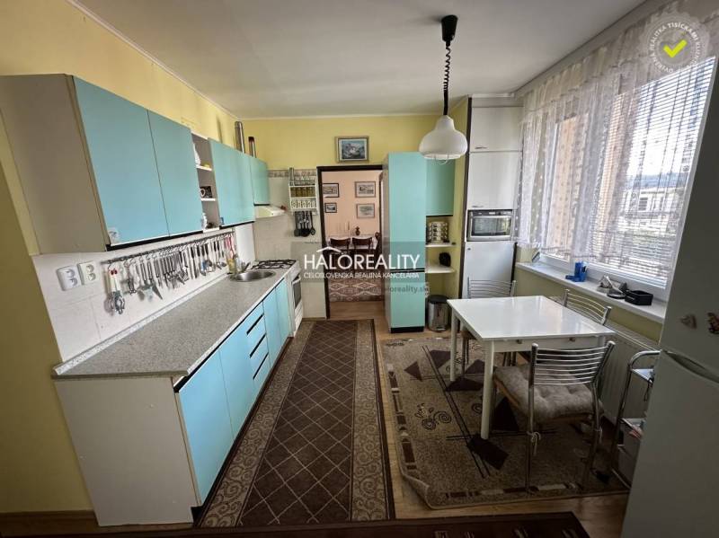 A kitchen in a 3-room apartment with blue cabinets and a dining table.