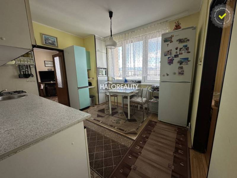 A kitchen in a 3-room apartment with a dining table, refrigerator, and gas stove.