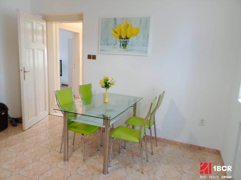 Dining area in a family house with a glass table and green chairs.