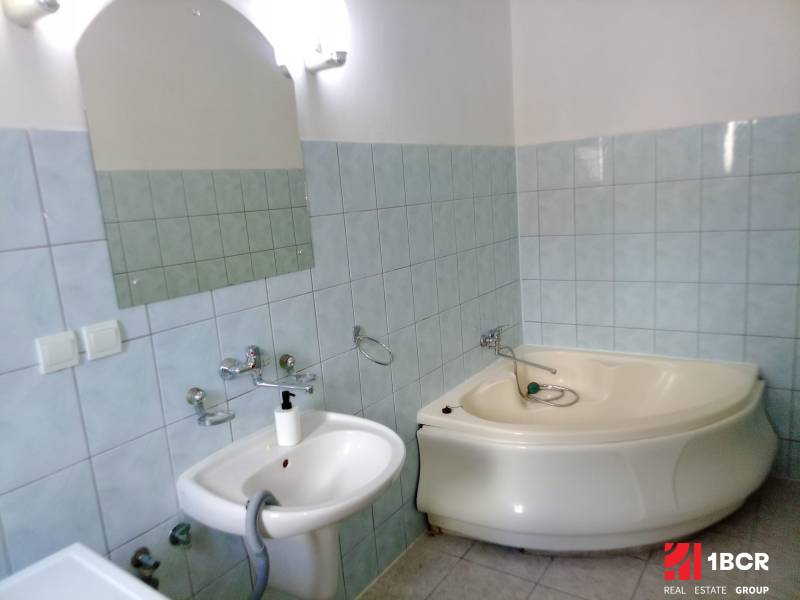 A bathroom in a family house with a branded hydromassage bathtub and a ceramic washbasin.