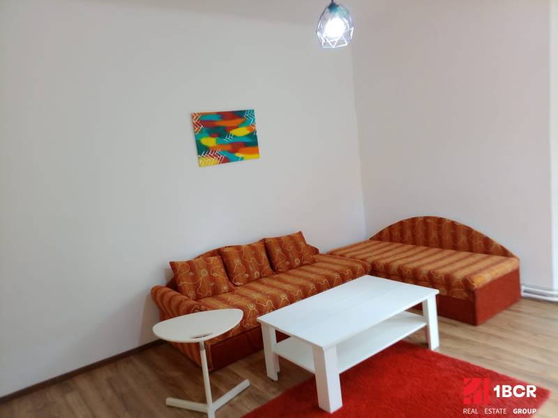 Orange sofa set in a family house with a wooden decor floor and a colorful painting.