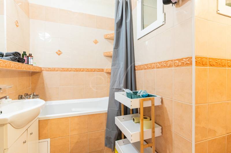 Bathroom with a bathtub, sink, and storage space in a 2-room apartment.