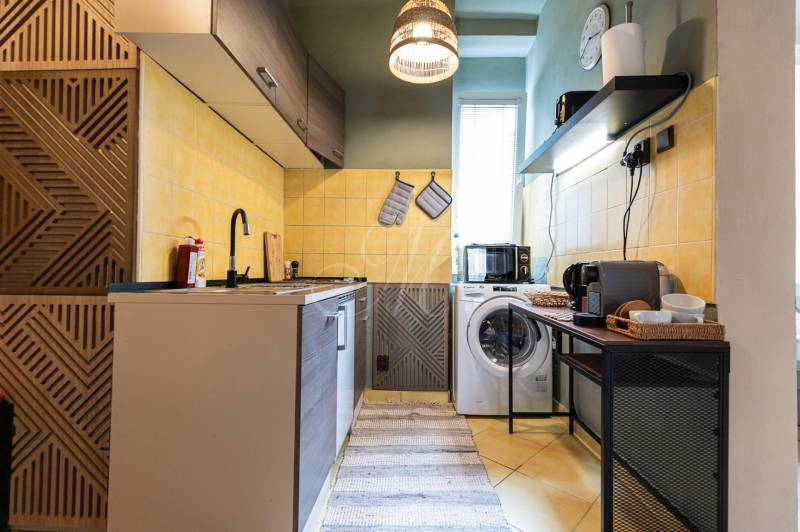 Kitchen in a 2-room apartment with a cooktop, washing machine, and coffee maker.