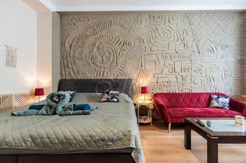 A stylish bedroom with a decorative wall, a bed, and a red sofa in a 2-room apartment.
