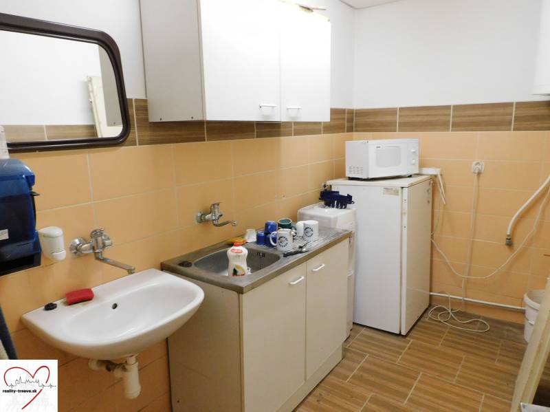 Interior of a kitchenette with a sink, microwave, and refrigerator in warehouse and hall spaces.