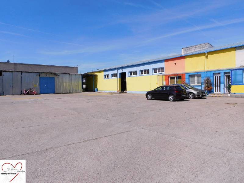 Colorful warehouse and hall buildings in Trnava with a parking lot and cars.