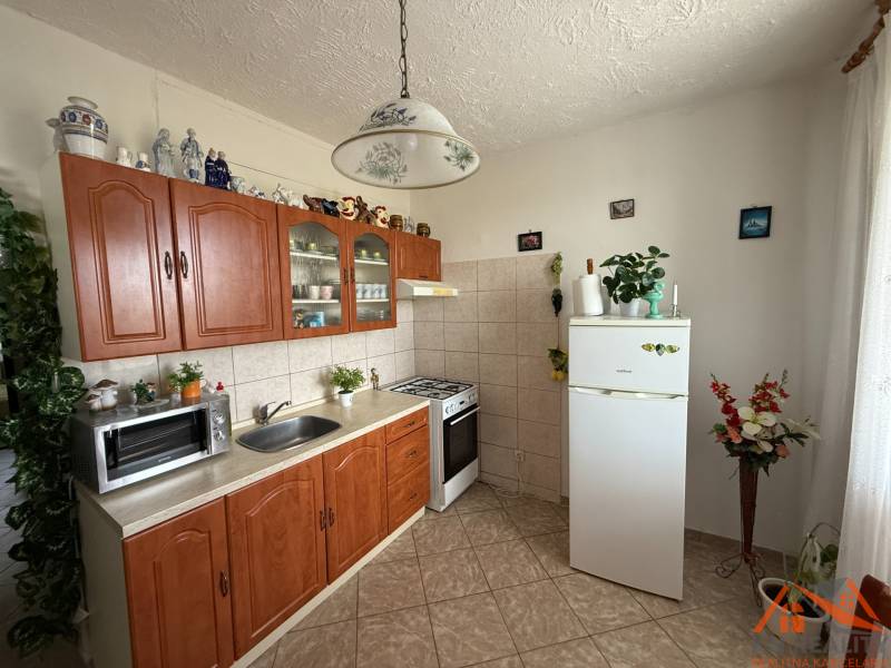 A kitchen in a 3-room apartment with a wooden cabinet, a white refrigerator, and ceramic decorations.