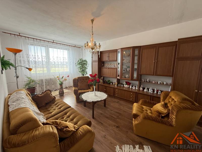 A living room with brown furniture and a couch in a three-room apartment, decorations on the wall.