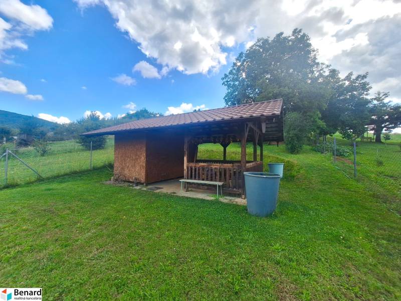 A shelter with a shingle roof on a plot in Bodovce, Bodovce, surrounded by greenery.