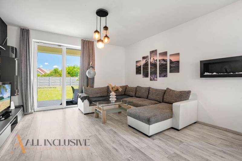 A living room in a family house with a comfortable sofa and glass doors leading to the garden.