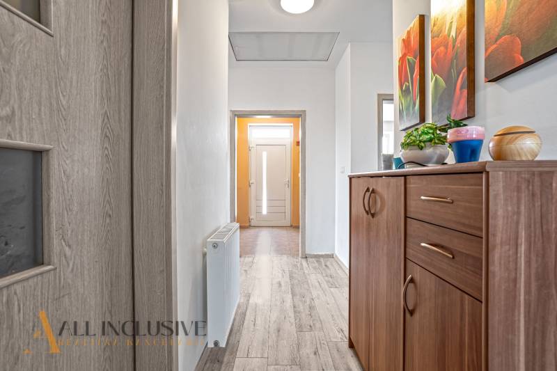 Hallway of a family house with entrance doors, a wooden chest of drawers, and wall decorations.