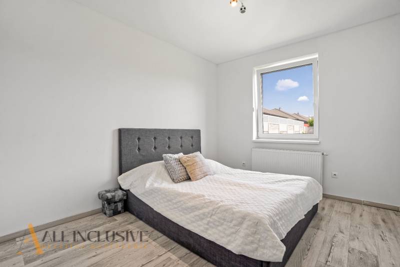 A bedroom in a family house with a single bed and a window, light wooden floors.