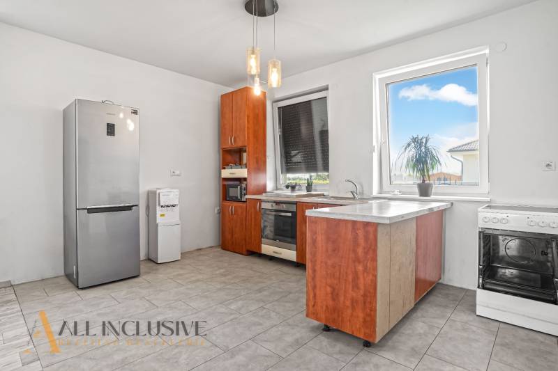A kitchen with wooden cabinets, a refrigerator, and appliances in a family house.