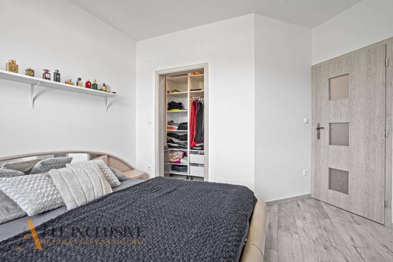 Bedroom with a bed in a family house, open wardrobe, and a shelf with perfumes.