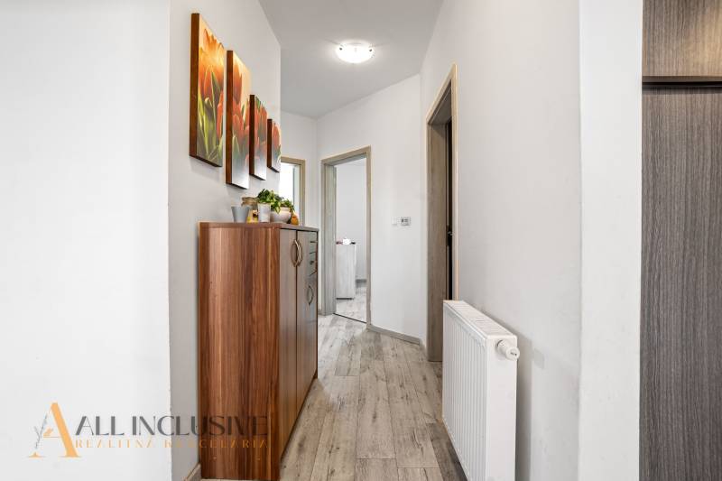 Hallway in a family house with a wooden chest of drawers and a colorful painting on the wall.