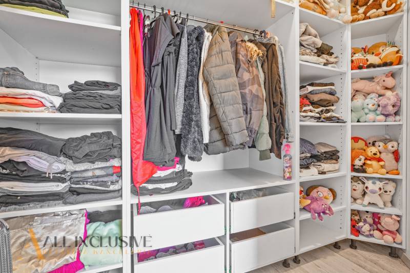 A wardrobe in a family house with clothes, toys, and stored items on shelves and in cabinets.