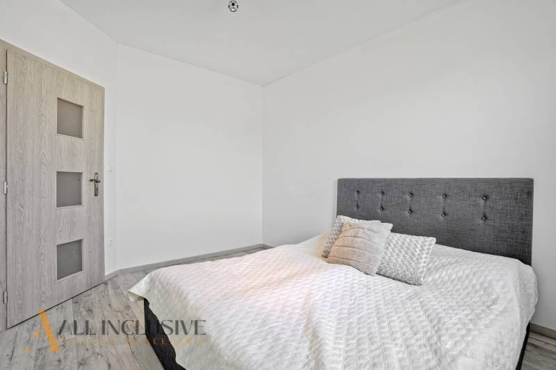 A bedroom in a family house with an upholstered headboard and wooden doors.