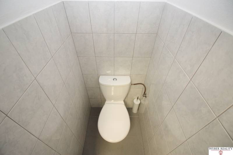A restroom with white tiles in commercial premises.