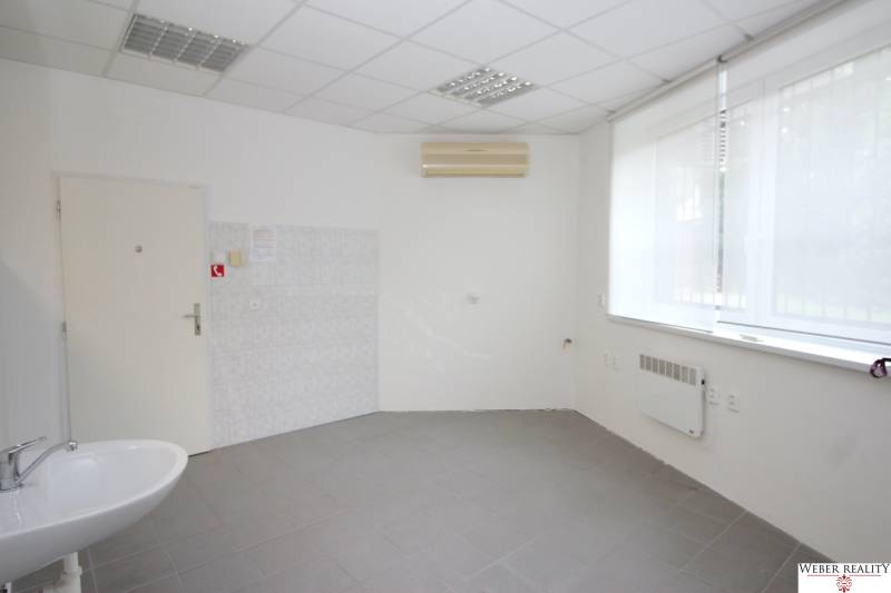 Commercial space with a sink, air conditioning, and a large window, available for rent.