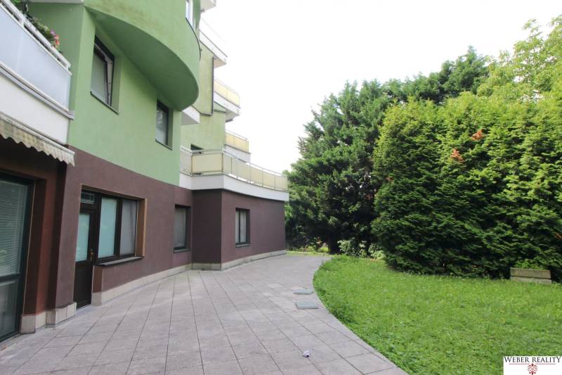 A building with a colorful facade and a terrace surrounded by greenery on Žatevná in Bratislava - Dúbravka.