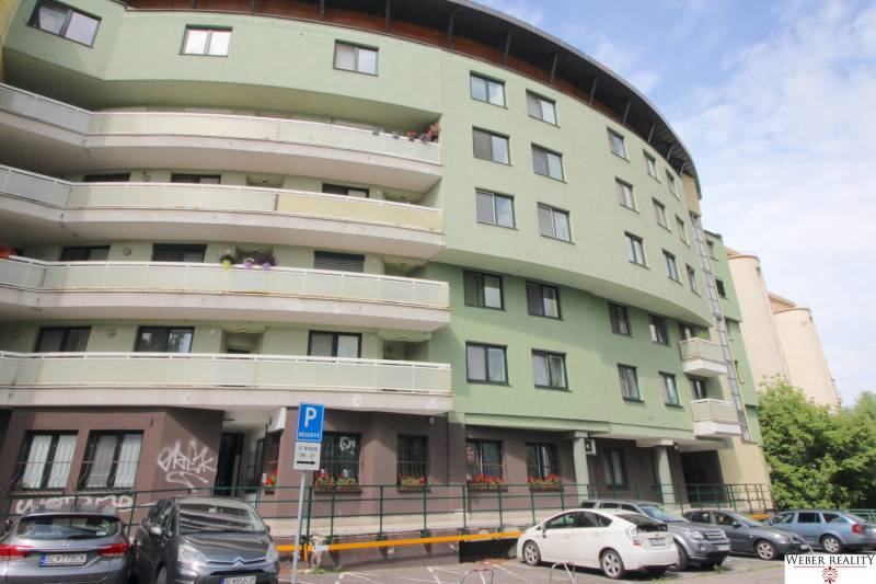 Apartment building with a curved structure, parking spaces in front of the entrance on Žatevná Street, Dúbravka.