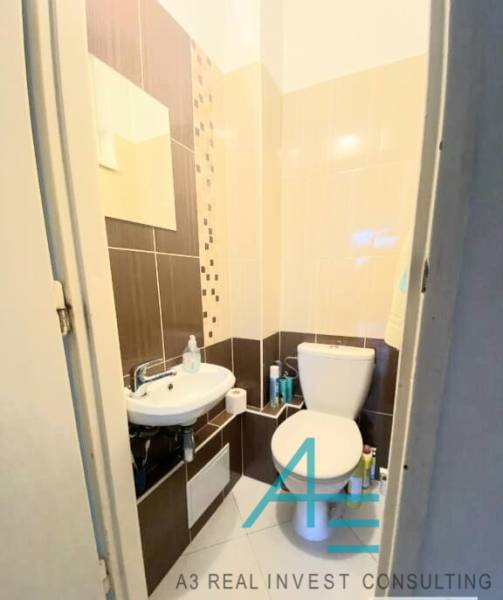 Bathroom with toilet in a 4-room apartment, with a sink and decorative tiles.