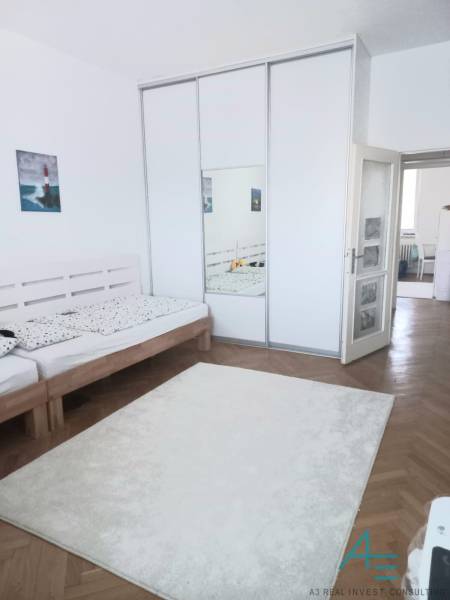 A bright bedroom with a large wardrobe and a wooden bed in a 4-room apartment.
