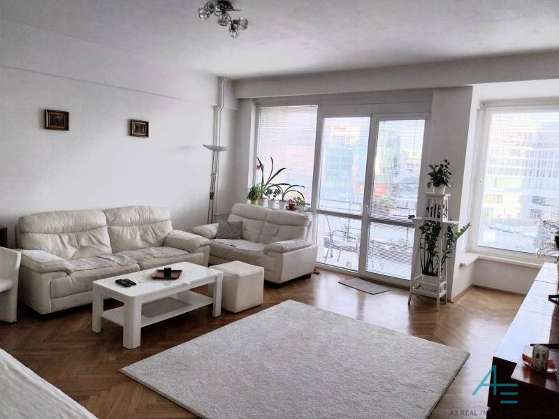 A bright living room with white sofas in a 4-room apartment, glass doors to the terrace.