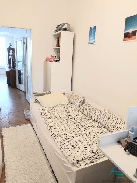 A room in a 4-room apartment with a bed, a shelf, and access to a balcony.