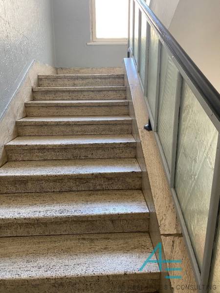 A staircase with a glass railing leads to a window in a 4-room apartment.