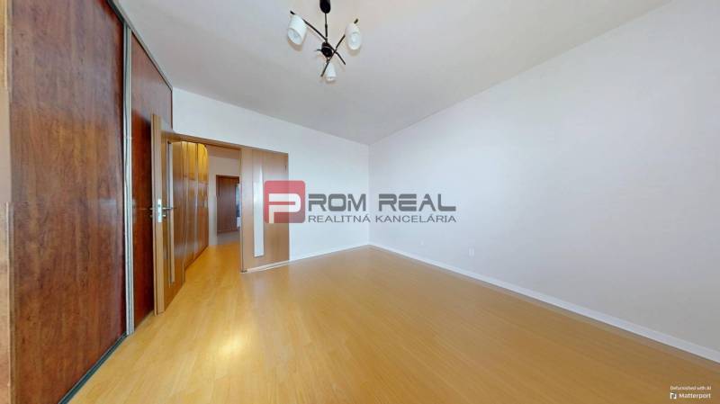 A room with a wooden floor, built-in wardrobe, and lighting in a 3-room apartment.