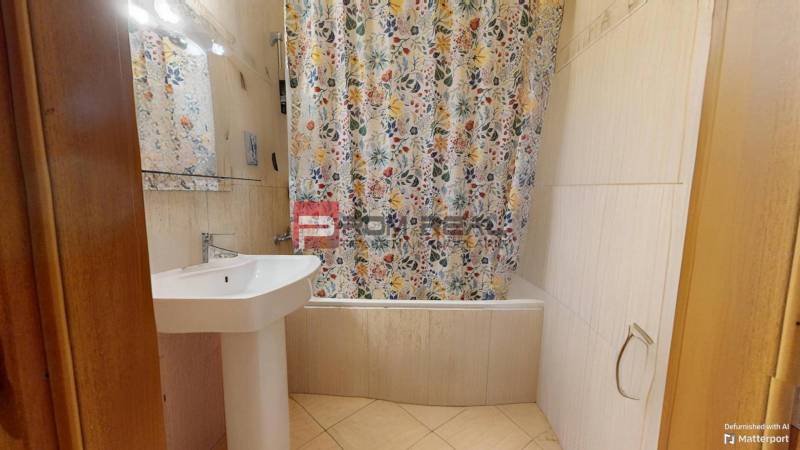 Bathroom with a sink and a bathtub with a patterned shower curtain in a 3-room apartment.