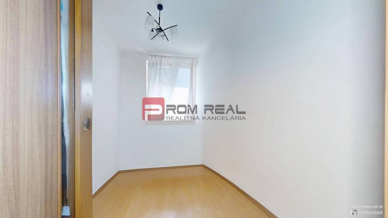 Empty room with white walls, laminate flooring, and a window in a 3-bedroom apartment.