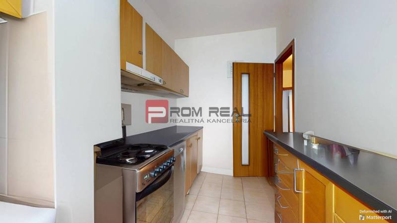 A kitchen in a 3-room apartment with light tiles and wooden cabinets.