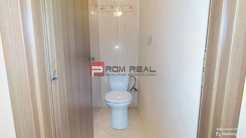 A toilet in a 3-room apartment with light tiles and wooden doors.