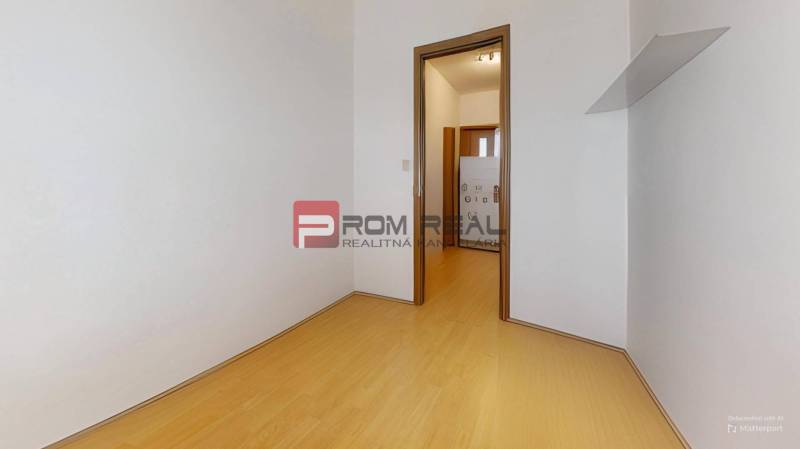 A room with a wooden floor and white walls in a 3-room apartment.