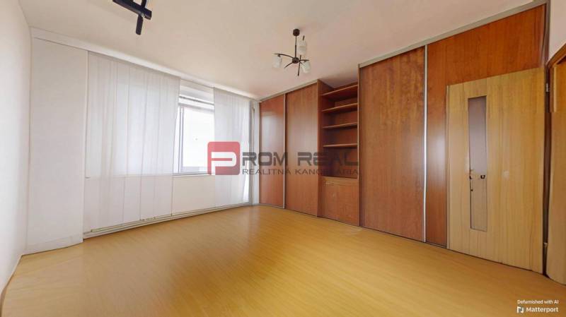 A room in a 3-room apartment with a wooden wardrobe and a ceiling light.