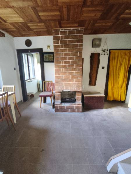 Interior of a cabin with a fireplace, window, and wooden decor flooring.