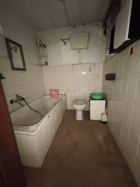 A bathroom in a cabin with a bathtub, toilet, and floor with a wooden decor.