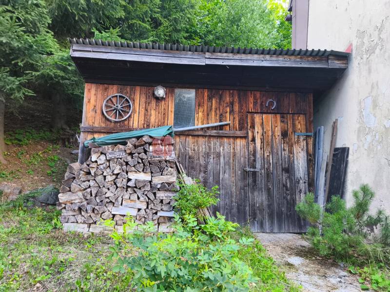 A wooden cabin in the forest at Kordíky in Banská Bystrica with stored wood.
