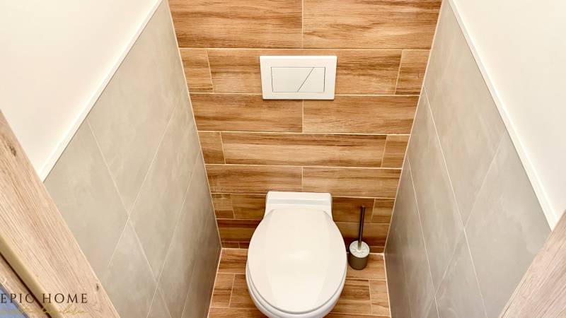 A toilet with wooden paneling in a studio apartment, harmoniously combining colors and textures.