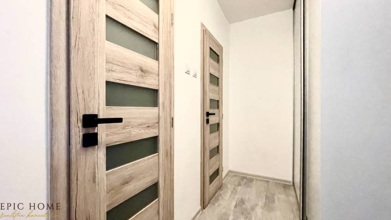 A hallway with light doors and a mirrored wardrobe in a one-room apartment.